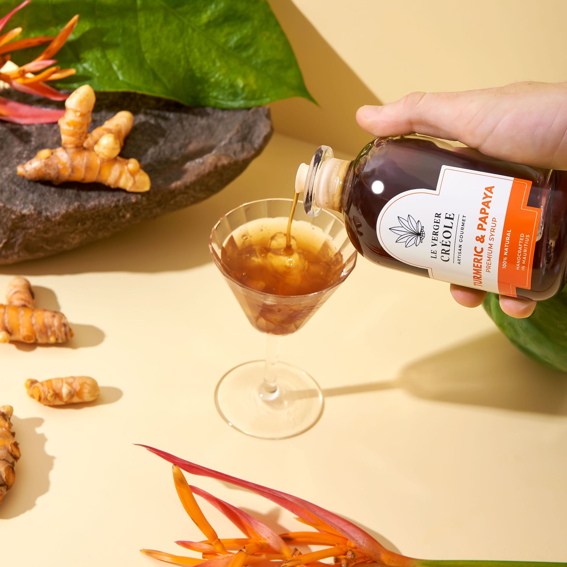 Le Verger Créole lifestyle still life with botanicals and a syrup bottle